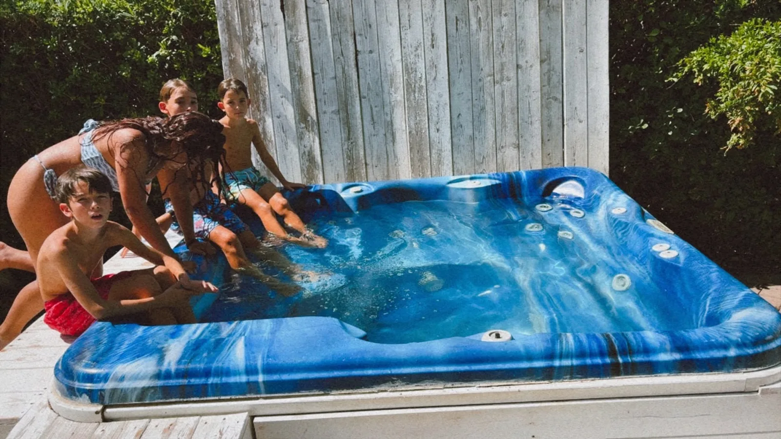 Młodzież siedząca na brzegu Maxi Jacuzzi Hotelu Viking z nogami w czystej wodzie