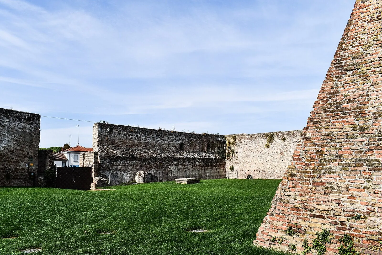 Le mura con scarpate di Castel Sismondo e il prato dell'area dell'antico fossato