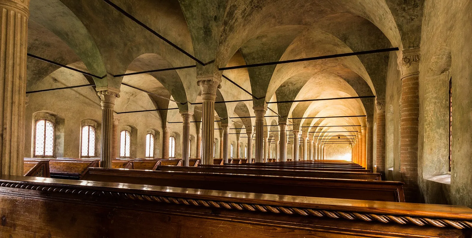Interno della Biblioteca Malatestiana di Cesena con le file di banchi in legno sotto le volte a tre navate
