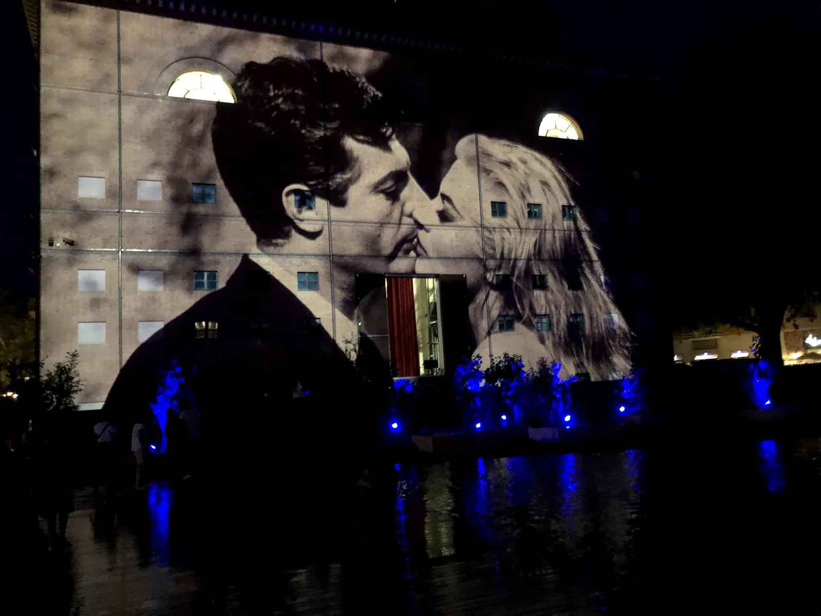 Una proyección de cine en la fachada del Fellini Museum en la piazza Malatesta de Rímini, de noche, con el estanque iluminado de azul