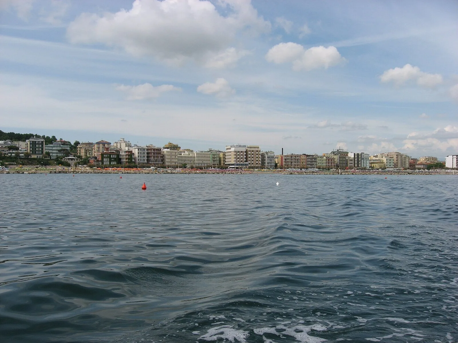 Die Uferfront von Gabicce Mare vom Wasser aus, mit dem Strand und den Gebäuden an der Strandpromenade