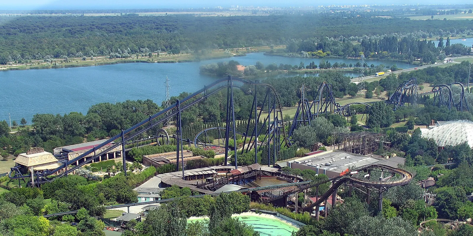 L'inverted coaster Katun visto dall'alto della ruota panoramica, con il lago e la pianura sullo sfondo.