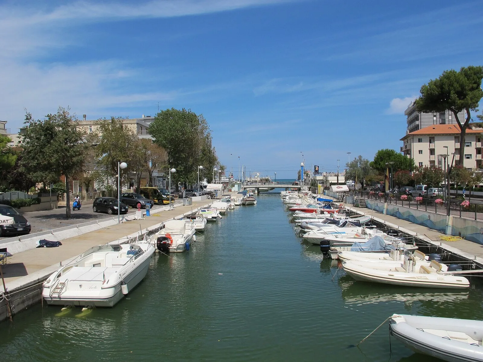 Il porto canale di Riccione con le barche ormeggiate lungo le banchine e il ponte sullo sfondo