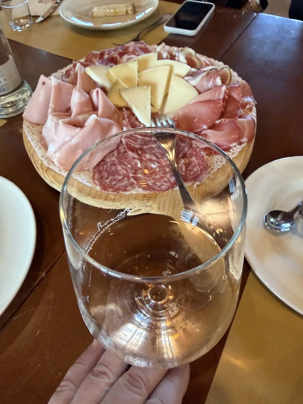 Ein Brett mit Wurst und Käse und ein Glas Wein in einer Osteria in Santarcangelo