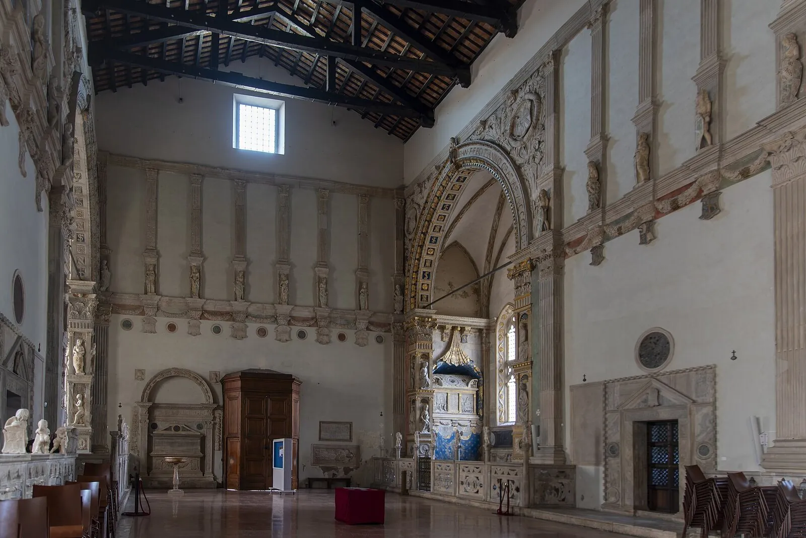 L'interno a navata unica con capriate a vista e le cappelle decorate
