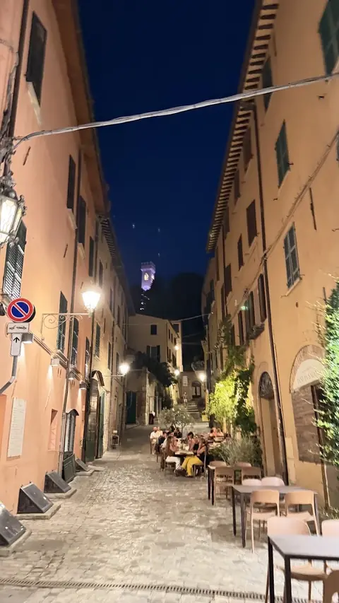 Una via del centro di Santarcangelo di sera, con i tavolini all’aperto e il Campanile illuminato in alto