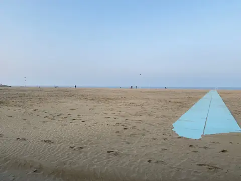 La spiaggia d’inverno sulla Riviera di Rimini, ampia e quasi deserta, con la passerella azzurra verso il mare