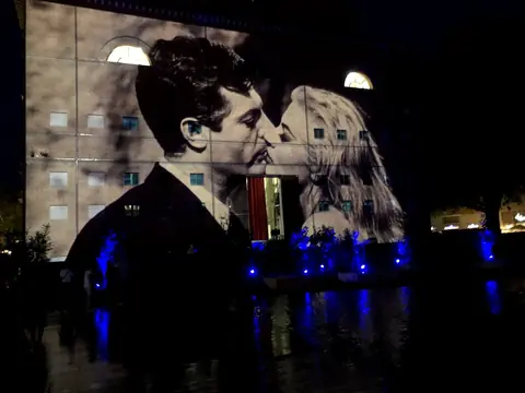 Una scena di un film di Fellini proiettata di notte sulla facciata del Teatro Galli, in piazza Malatesta, con la vasca illuminata di blu