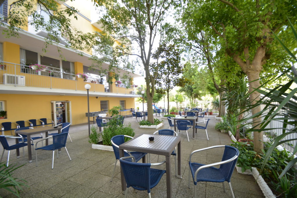Il giardino alberato dell'Hotel Viking con i tavoli all'ombra