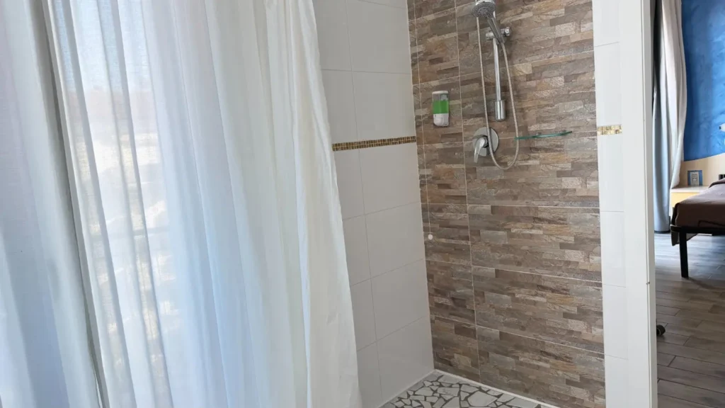 Doccia a filo pavimento con tenda e doccetta su asta nella camera Comfort dell'Hotel Viking