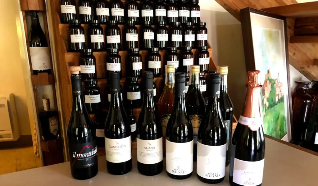 Bottiglie di vino della Tenuta Saiano davanti ai vasetti di erbe e spezie dell'Olfattorio