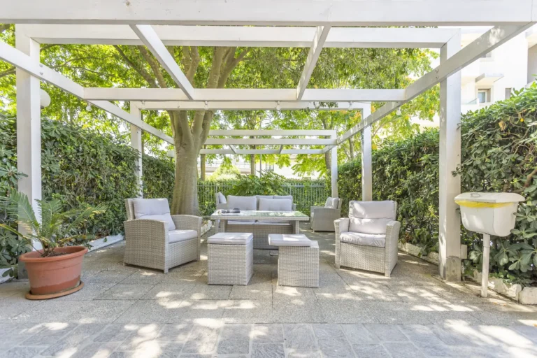 Salotto in rattan sotto il pergolato bianco nel giardino dell'Hotel Viking