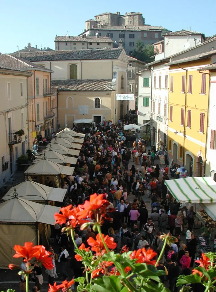 La Fiera del Tartufo Bianco a Sant'Agata Feltria: bancarelle e visitatori nella via principale, con la Rocca Fregoso in alto